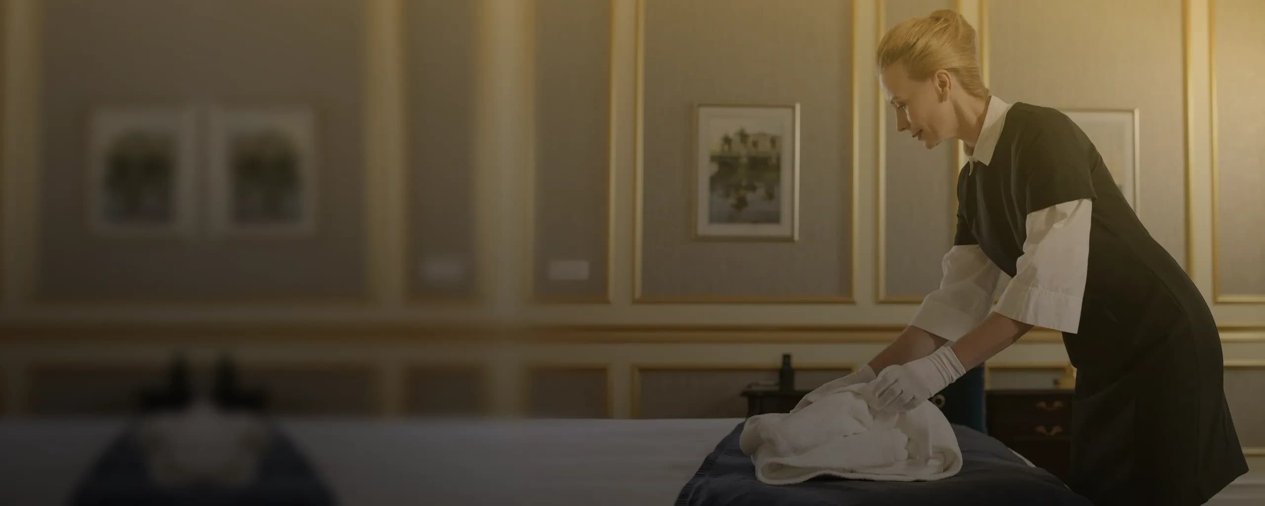 A housekeeper folding fresh towels on a newly made bed