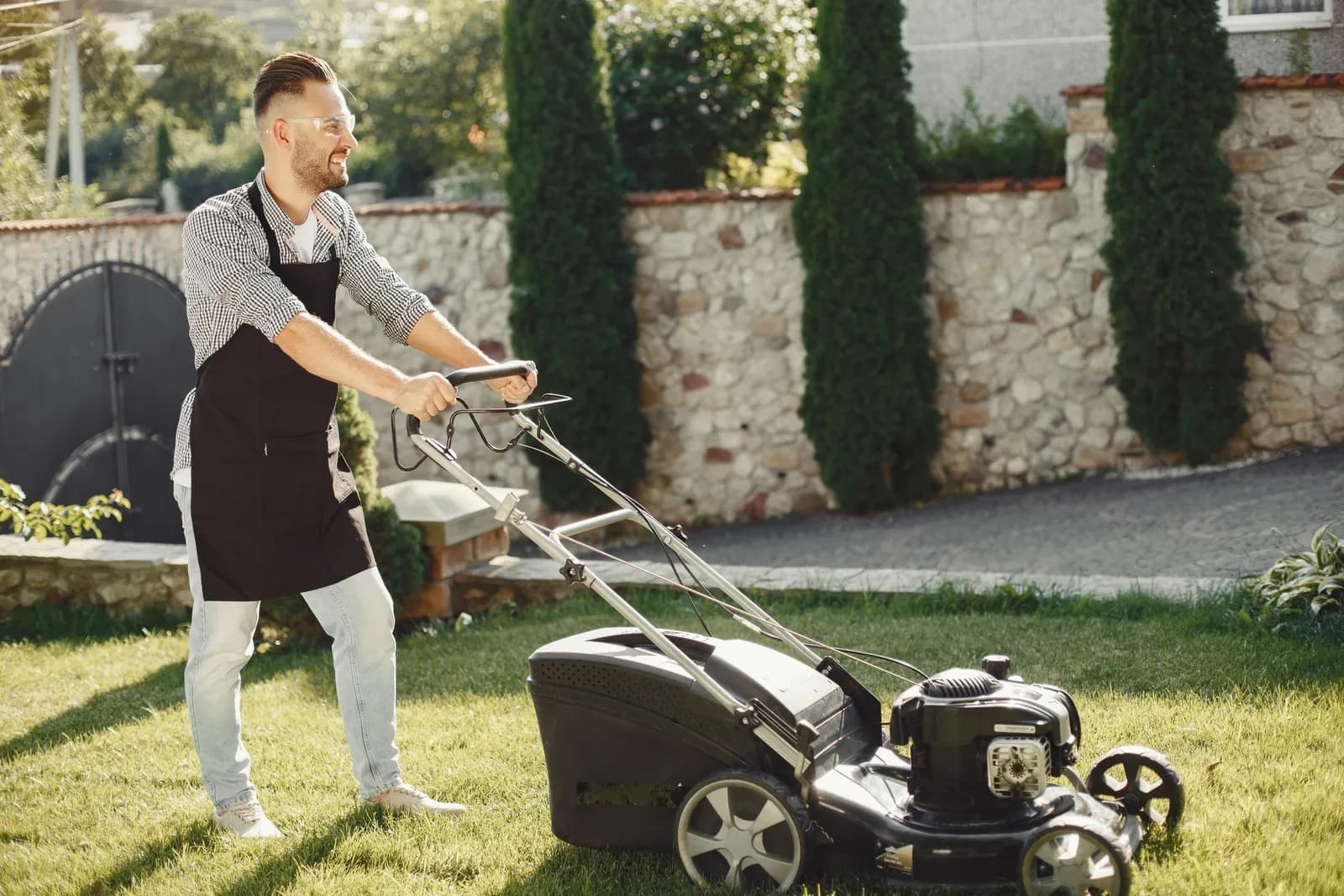 A gardener mowing a lawn with a push mower